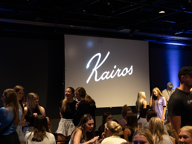 Students talking, Kairos logo projected on screen