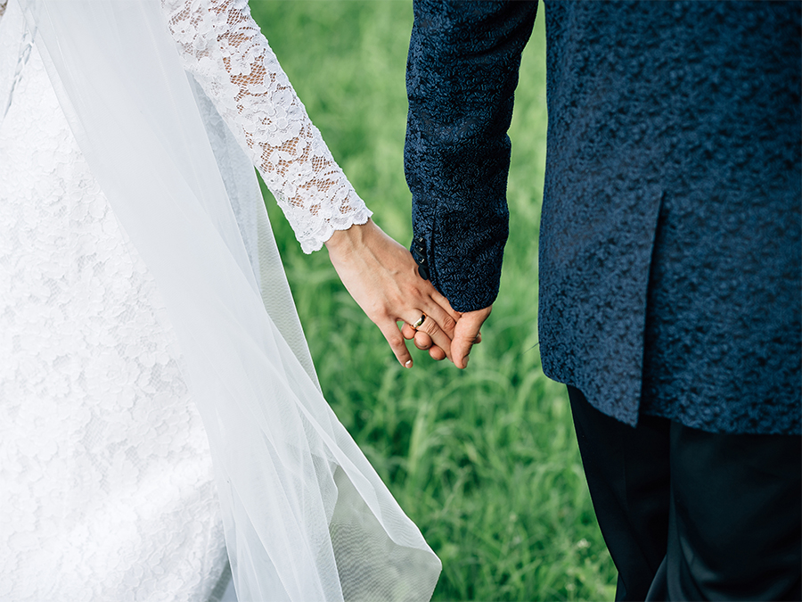 Couple holding hands with wedding rings